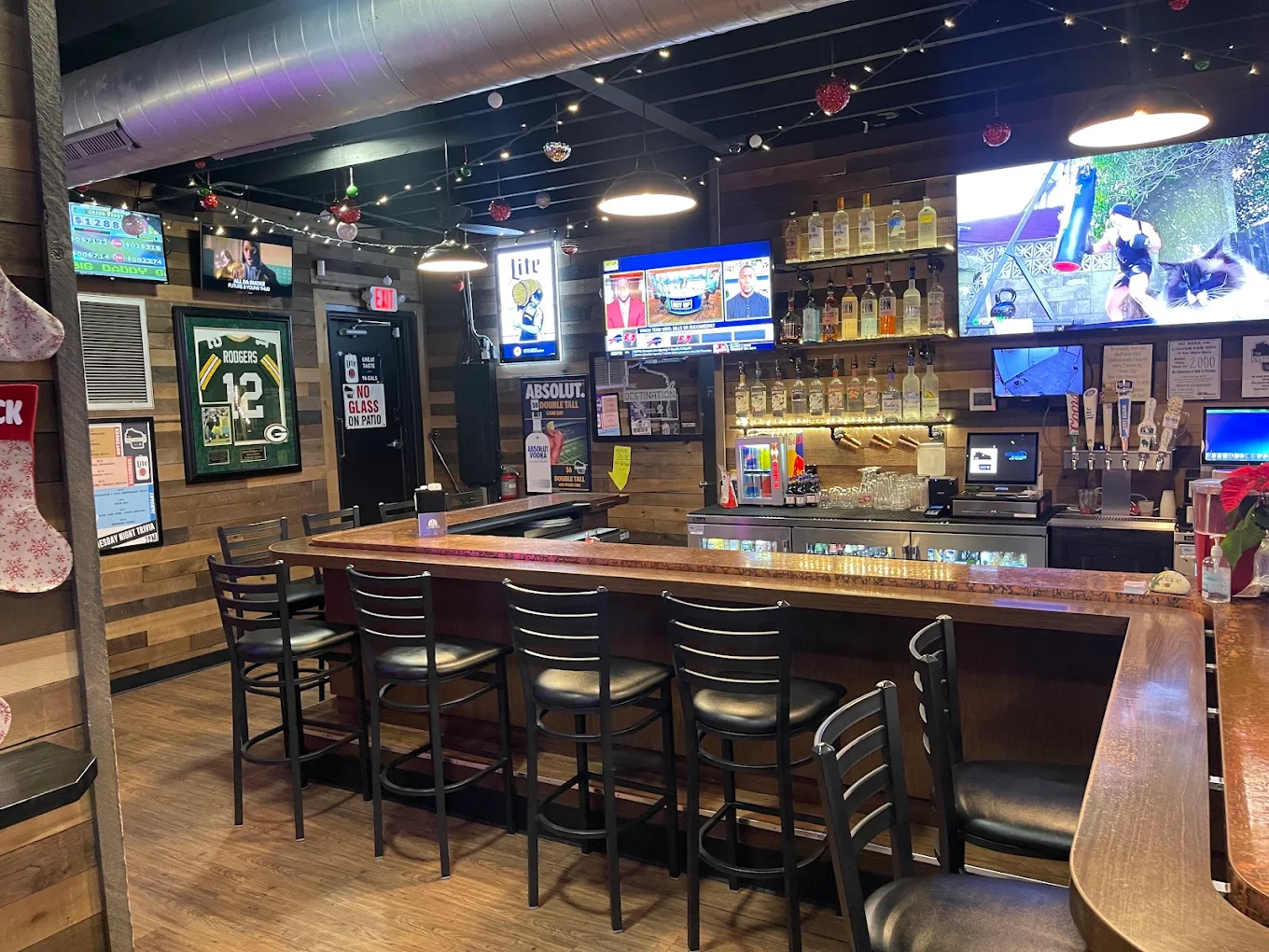 The main bar at The Destination: copper bar top, row of stools, reclaimed wood walls, sports on the TVs and a framed Packers jersey